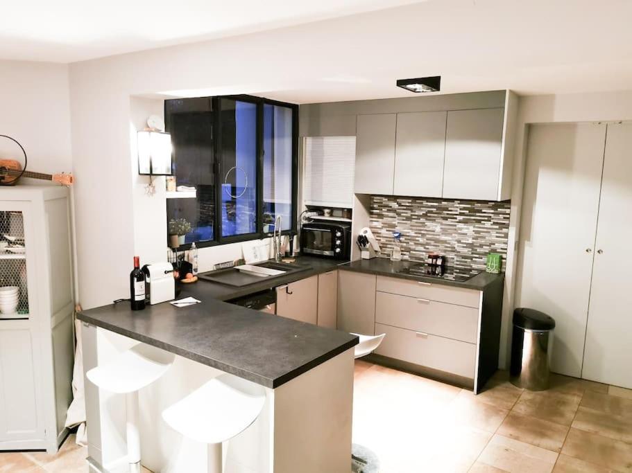 a kitchen with white cabinets and a black counter top at Maison Exceptionnelle ! Vue tour Eiffel et Paris in Suresnes