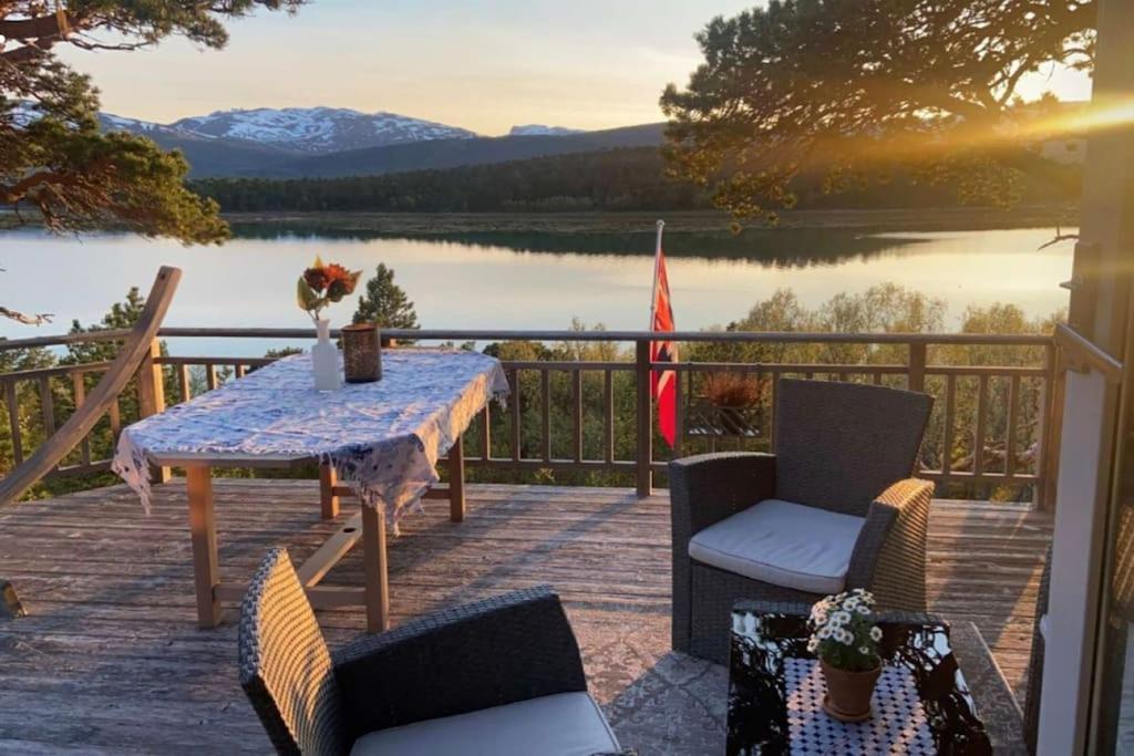 a table and chairs on a deck with a view of a lake at Drømmehytta på Senja in Tranøya
