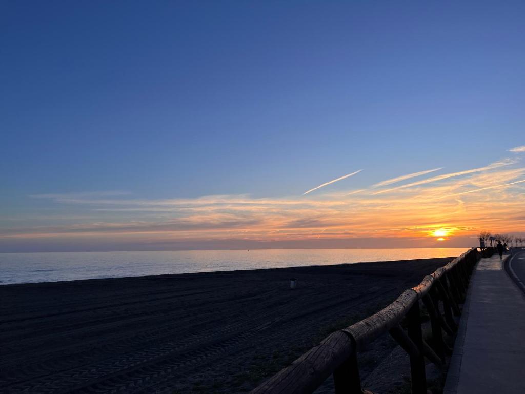 a sunset on a beach with the ocean and a fence at Casa Las Toro Playa in Chilches