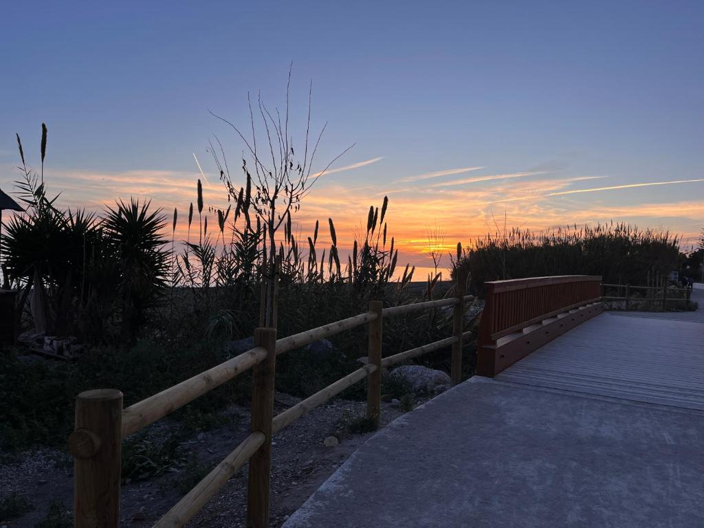 a wooden fence next to a walkway with a sunset in the background at Casa Las Toro Playa in Chilches