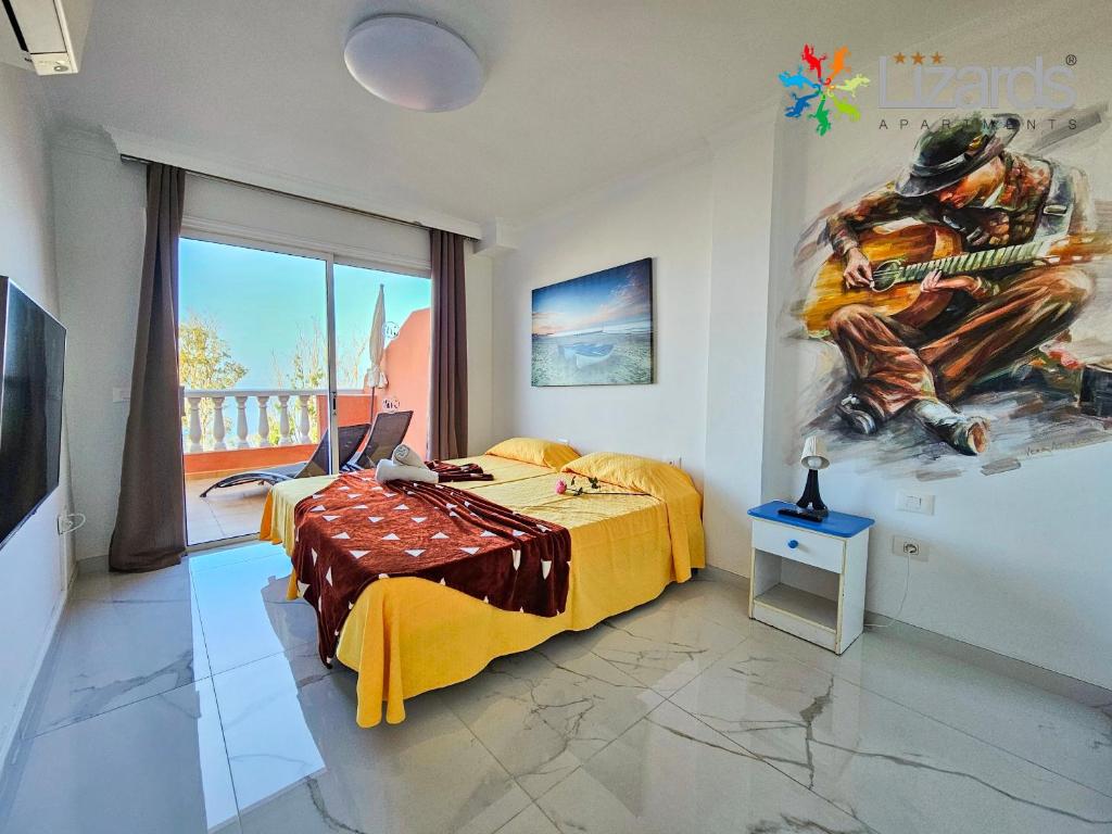 1 dormitorio con 1 cama y una pintura en la pared en 7Lizards - Ocean View Apartments, en Puerto de Santiago