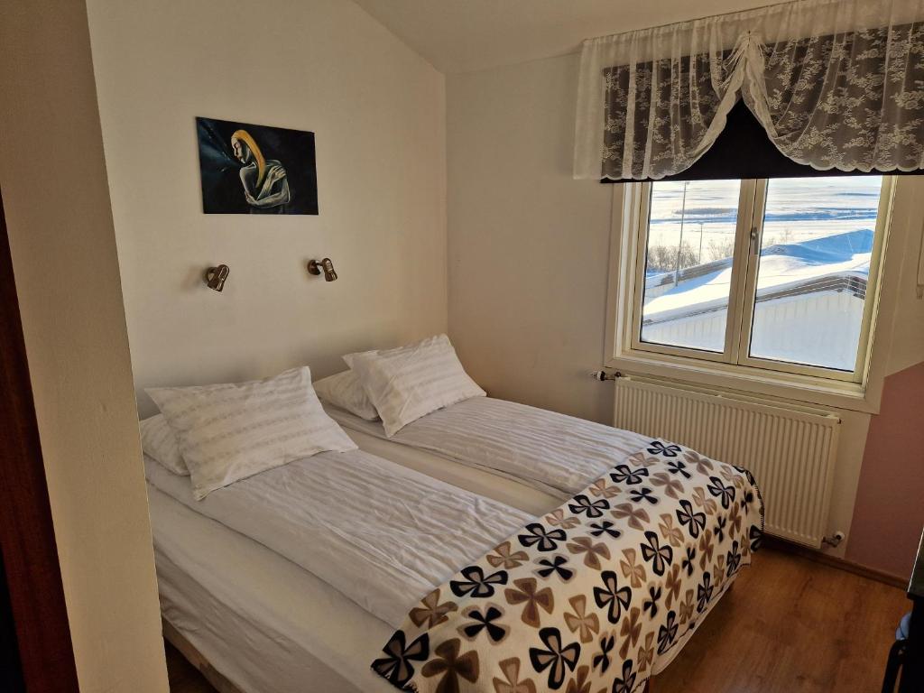 a bed in a room with a window at Gauksmýri guesthouse in Hvammstangi