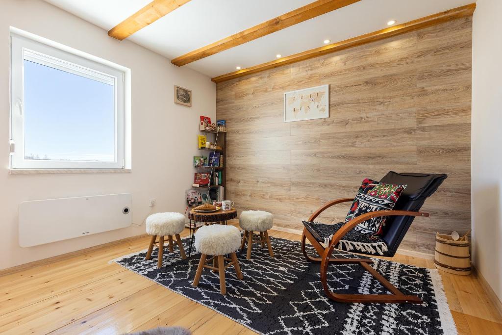 una sala de estar con una pared de madera y una silla y ools en Vikendica Bjelašnica Lukavac en Bjelašnica