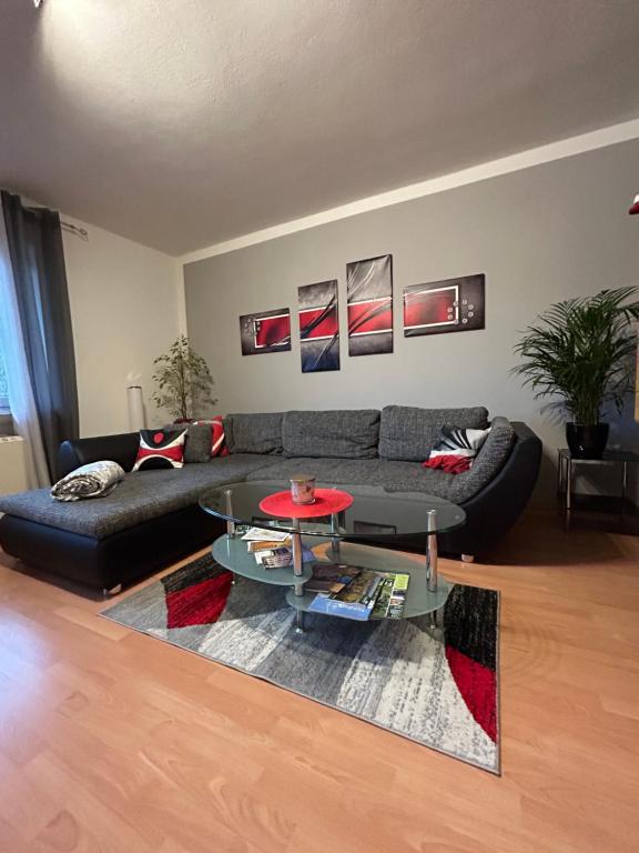 a living room with a black couch and a glass table at Große helle Ferienwohnung mit Balkon, ruhig gelegen mit guter Verkehrsanbindung in Bad Berneck im Fichtelgebirge