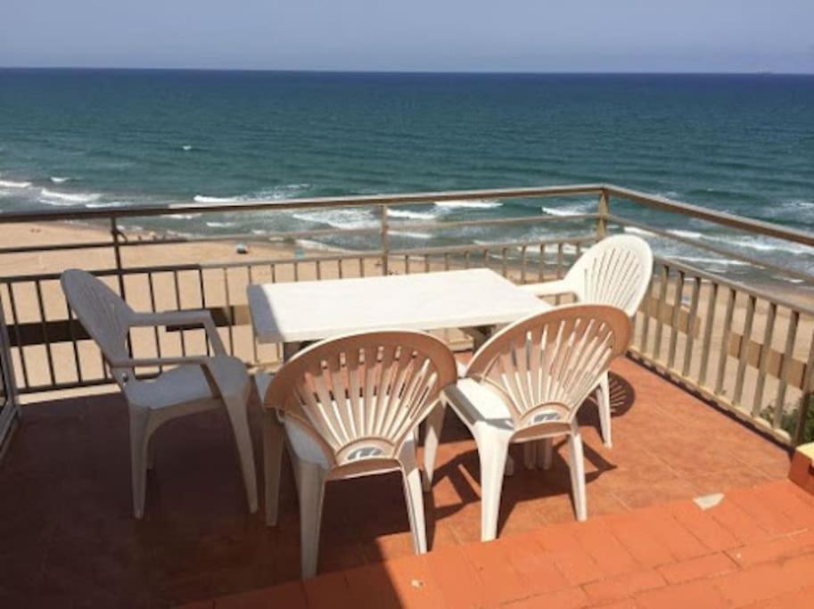 una mesa y sillas en un balcón con vistas al océano en PRIMERA LINEA DE PLAYA-CULLERA, en Cullera