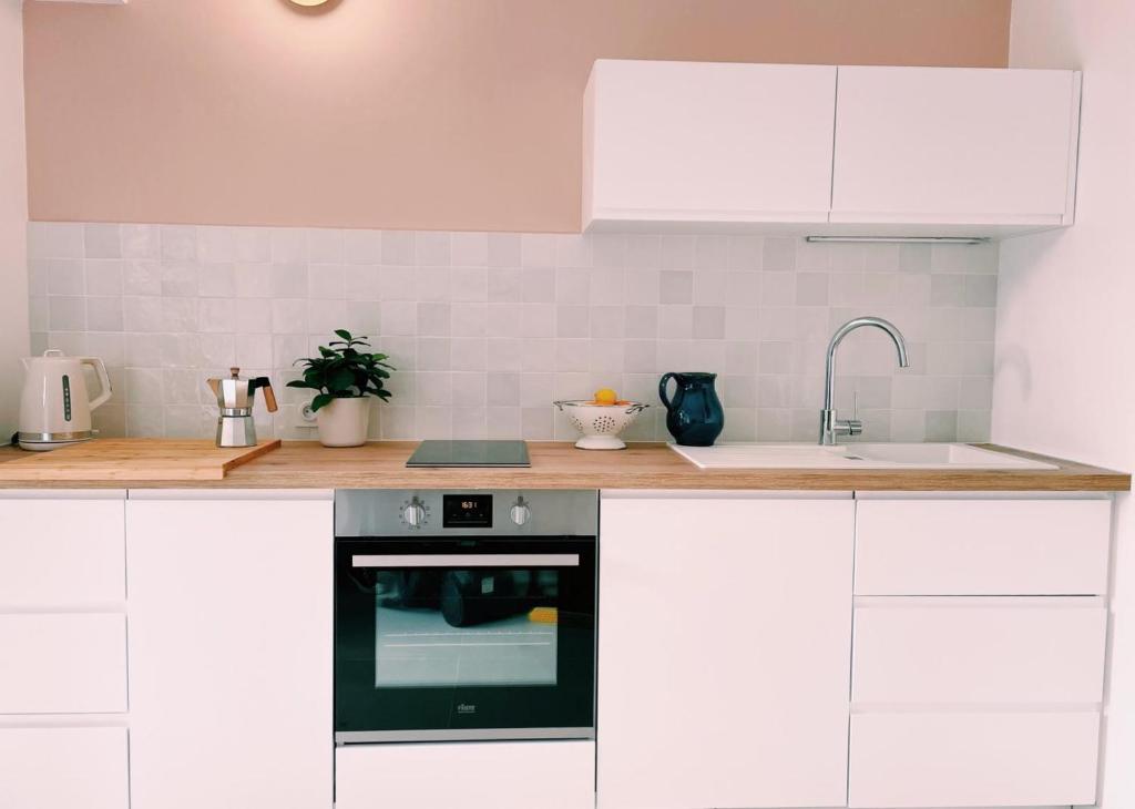 a kitchen with white cabinets and a sink and an oven at Studio d'architecte à 150 m de la plage in Royan