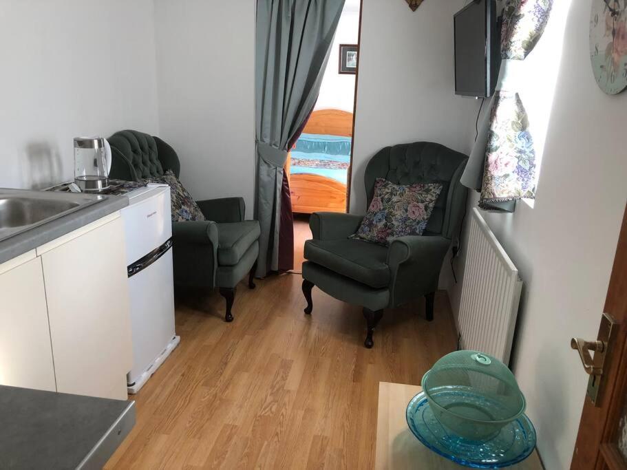 uma cozinha com duas cadeiras e um lavatório num quarto em Private, homely, 1 bedroom apartment SW London. em Hanworth