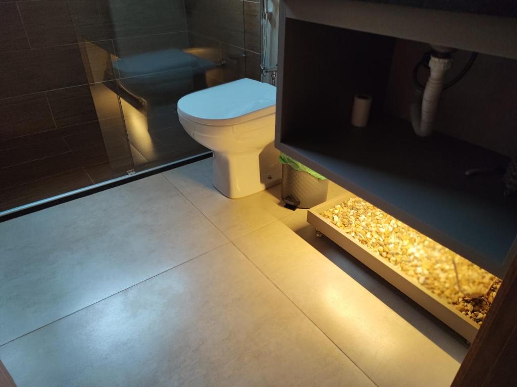 a bathroom with a toilet with a light on the floor at Suíte Alto Padrão in Uberaba