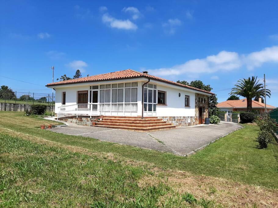 een wit huis met een palmboom ervoor bij Casa Margarita in Cudillero