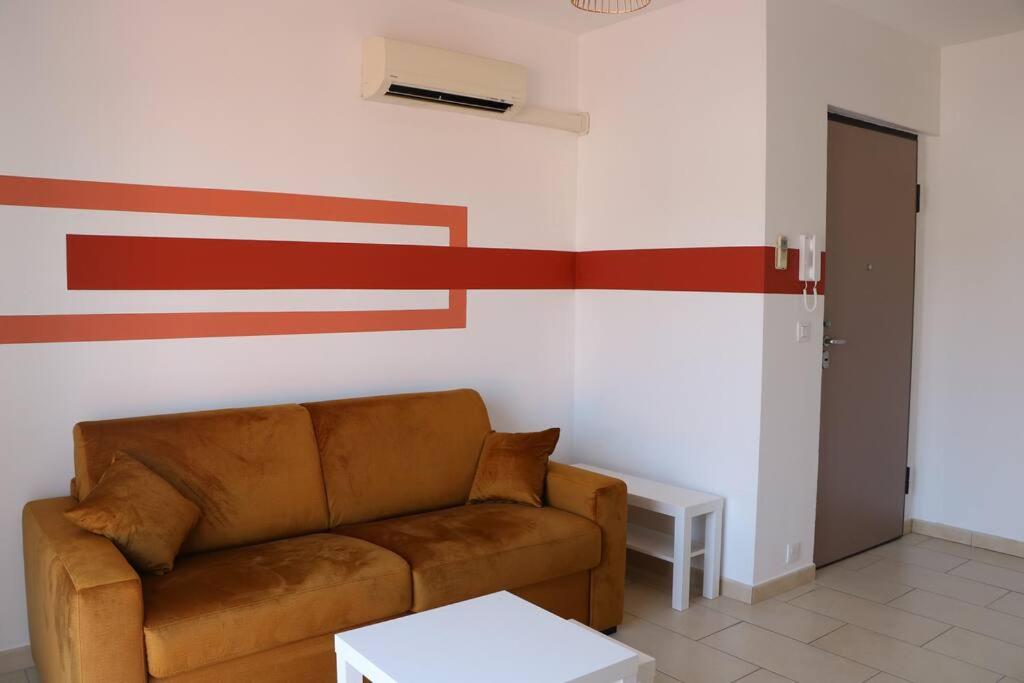 ein Wohnzimmer mit einem braunen Sofa und roten Streifen an der Wand in der Unterkunft Charmant Studio au calme in Saint-Laurent-du-Var