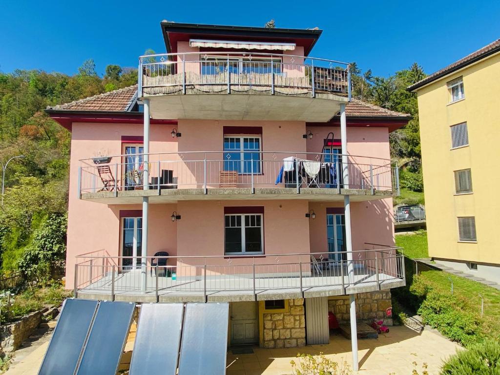 ein rosafarbenes Haus mit Balkon darüber in der Unterkunft Chez Carole (4 pièces) in Neuenburg