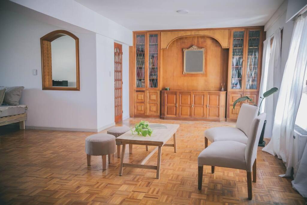 ein Wohnzimmer mit einem Tisch, Stühlen und einem Spiegel in der Unterkunft Amplio departamento en Mitre 565 in Mendoza