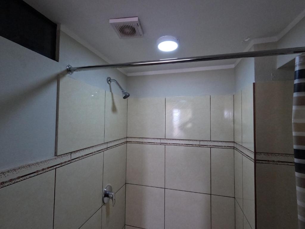 uma casa de banho com um chuveiro com paredes brancas em Millpu Hostal em Ayacucho