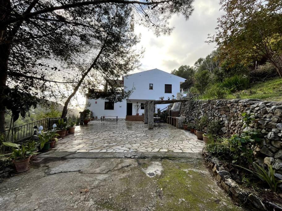 una casa blanca en una colina con una pared de piedra en Villa Victoria, en Cómpeta