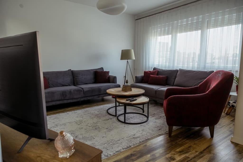 a living room with a couch and a tv at White Apartment Prishtina in Pristina