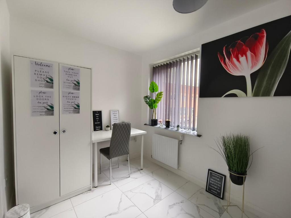 ein weißes Büro mit einem Schreibtisch und einer roten Blume an der Wand in der Unterkunft Shared House - 10 mins from Piccadilly Station/Man Uni/O2 Apollo in Manchester