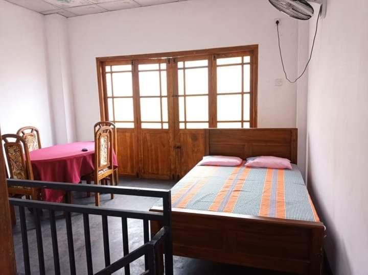 a bedroom with a bed and a table and a window at Puraya'S Lodge in Anuradhapura