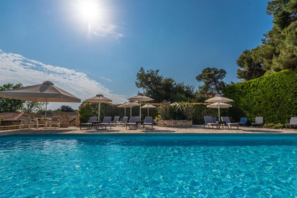 a swimming pool with chairs and umbrellas at AQUARIUS HOTEL in Vasilikos