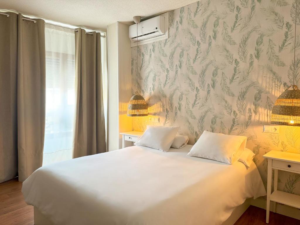 a bedroom with a white bed and a wall at Hotel Plaza Mayor in Ocaña