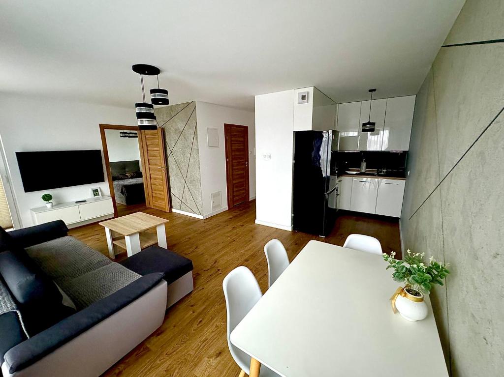 ein Wohnzimmer mit einem Sofa und einem Tisch in der Unterkunft Jurajska Plaza - Nowoczesny apartament z osobną sypialnią, Parking GRATIS - HK Apartaments Kielce in Kielce