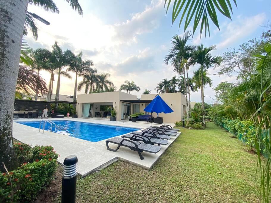 uma piscina com espreguiçadeiras e um guarda-sol azul em Casa de campo Villavicencio em Villavicencio