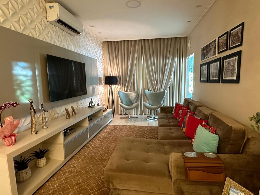 a living room with a large couch and a television at Quarto em casa de condominio fechado in Santarém