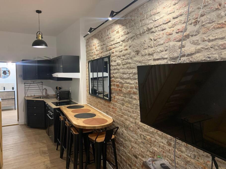 a kitchen with a wooden table and a brick wall at Maison centre-ville Cambrai in Cambrai