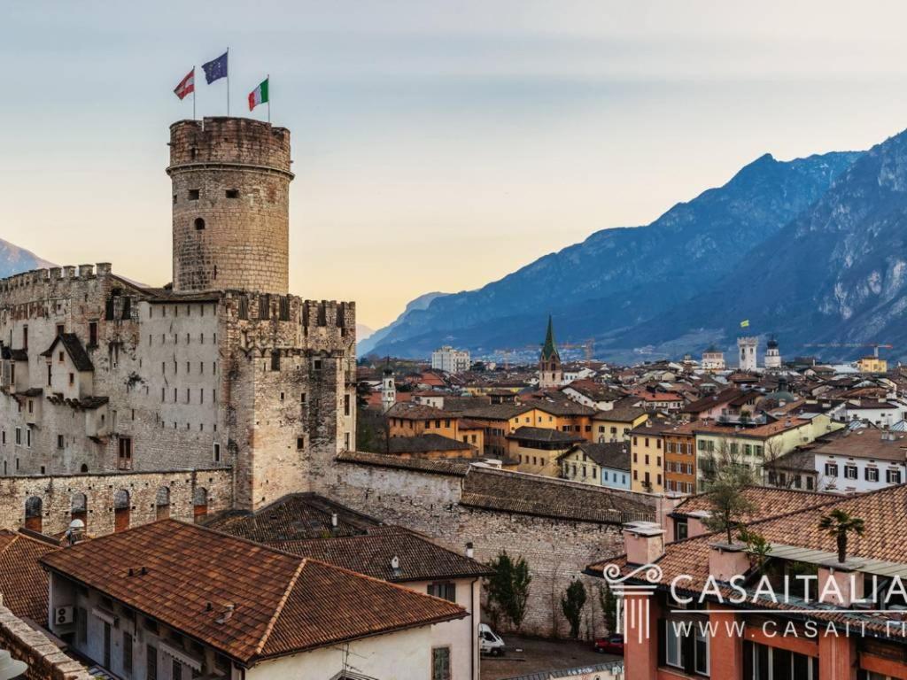 Un castello con due bandiere sopra una città di Residence Al Castello a Trento