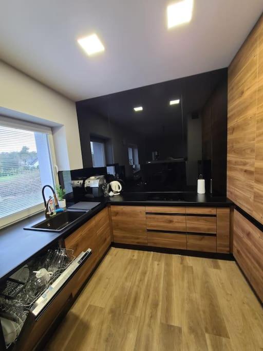 a kitchen with black counters and a wooden floor at Domek Bocianie Gniazdo in Stradomka