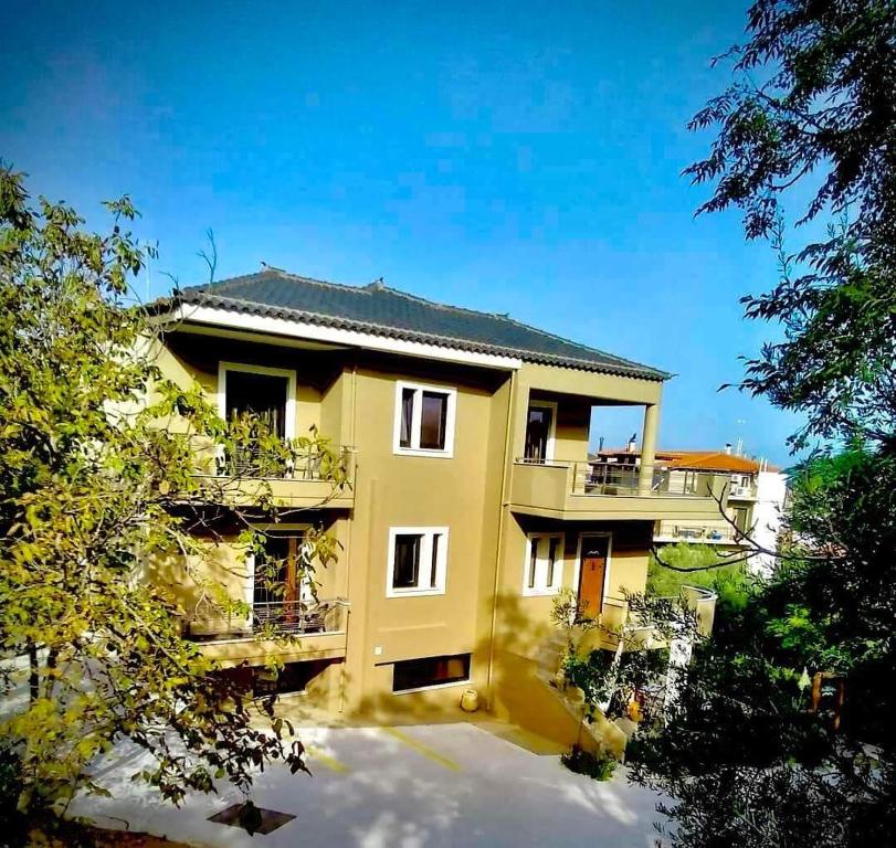 ein gelbes Haus mit einem Balkon und Bäumen in der Unterkunft Ducato di Aria in Nafplio