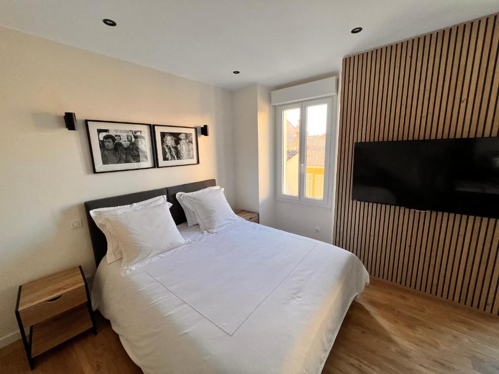 une chambre avec un lit blanc et une télévision à écran plat dans l'établissement Appartement comme une suite d’hôtel, à Cannes