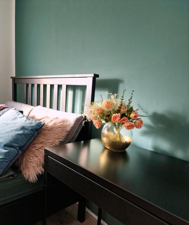 een vaas met bloemen op een tafel naast een bed bij Ella Green Apartments in Gratkorn
