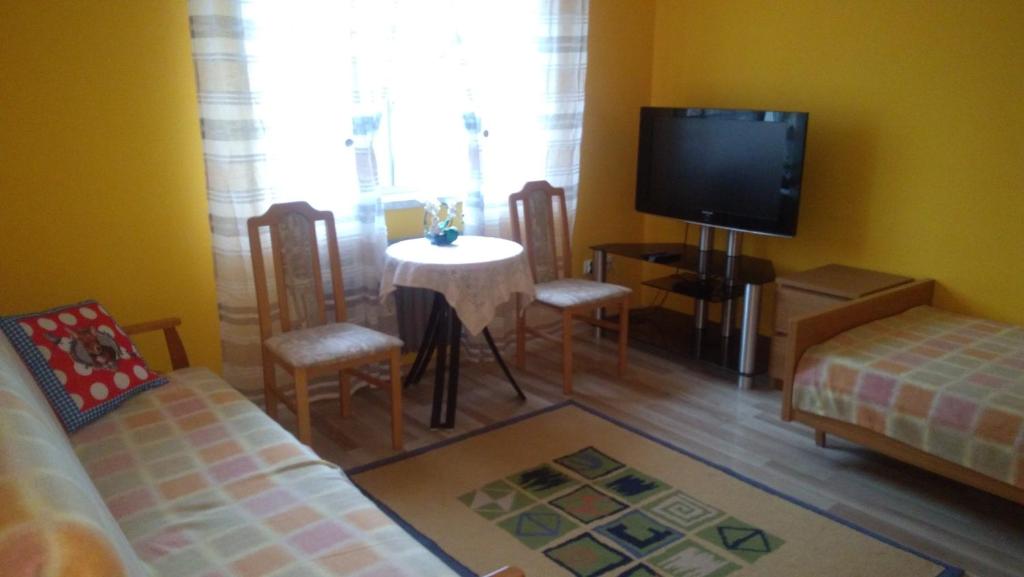 uma sala de estar com uma televisão e uma mesa e cadeiras em Pokoje Goscinne Buzuki em Ciechanów