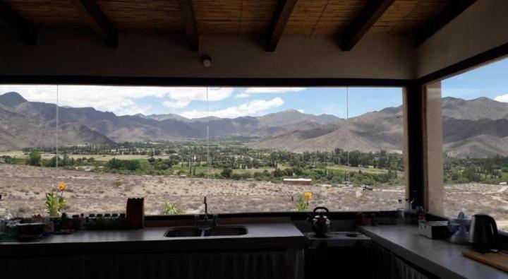 a kitchen with a view of the mountains from a window at Cabaña Abra del Monte Monohambiente in Cachí