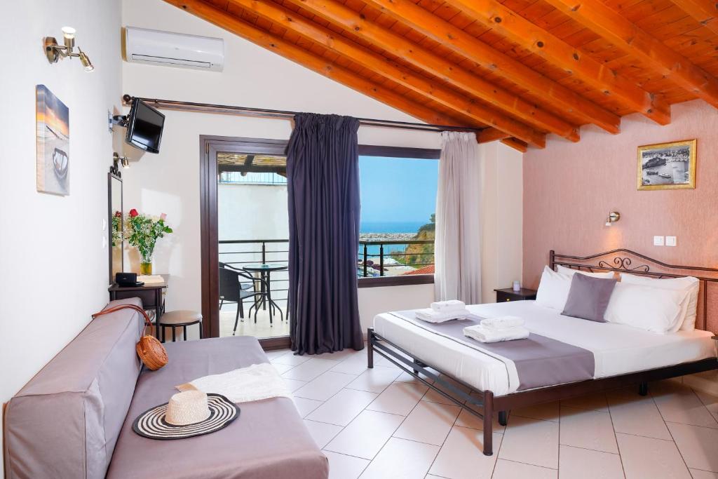 a bedroom with a bed and a couch and a balcony at Thassos Neorion in Limenaria