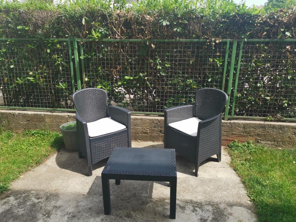 three chairs and a table in front of a fence at Art Apartment in Podgorica
