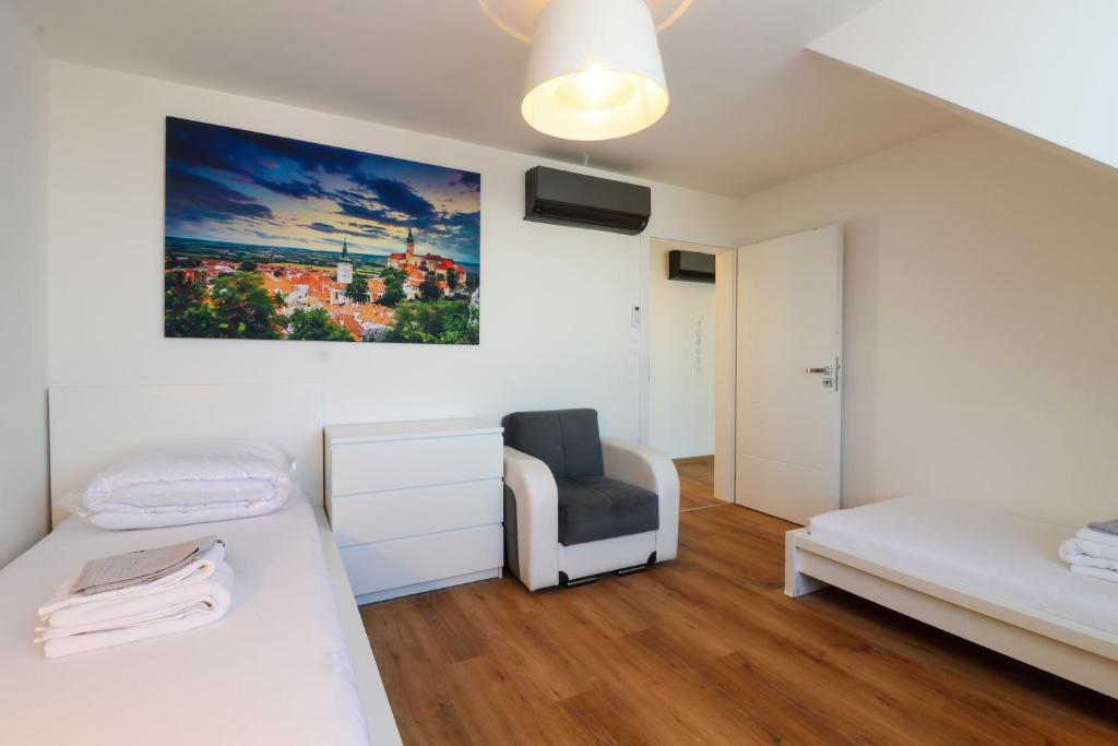 a room with two beds and a chair in it at Apartmány Mikulovské zahrady in Mikulov