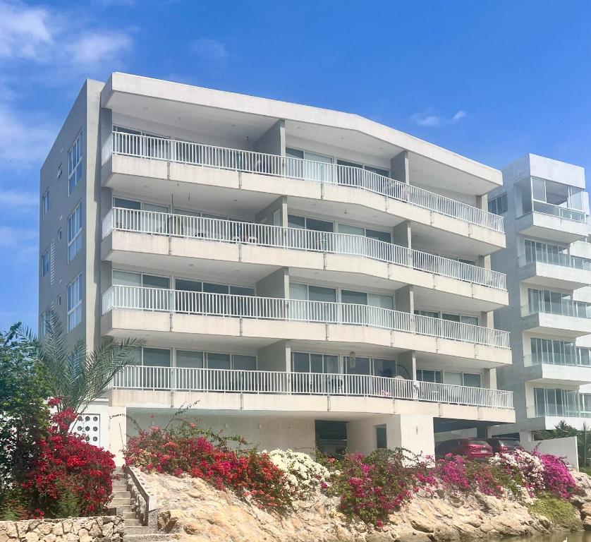 an apartment building with balconies and flowers in front of it at Departamento al pie del mar - Punta Blanca in Punta Blanca