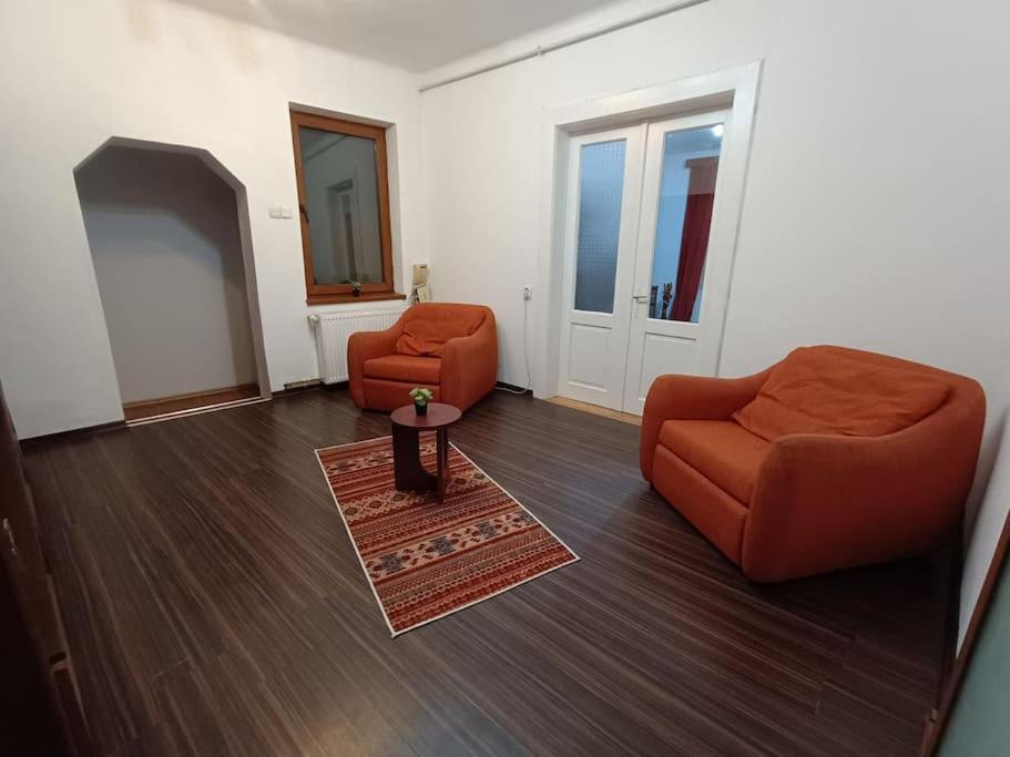 salon z 2 pomarańczowymi krzesłami i stołem w obiekcie Casa Iulia w Braszowie