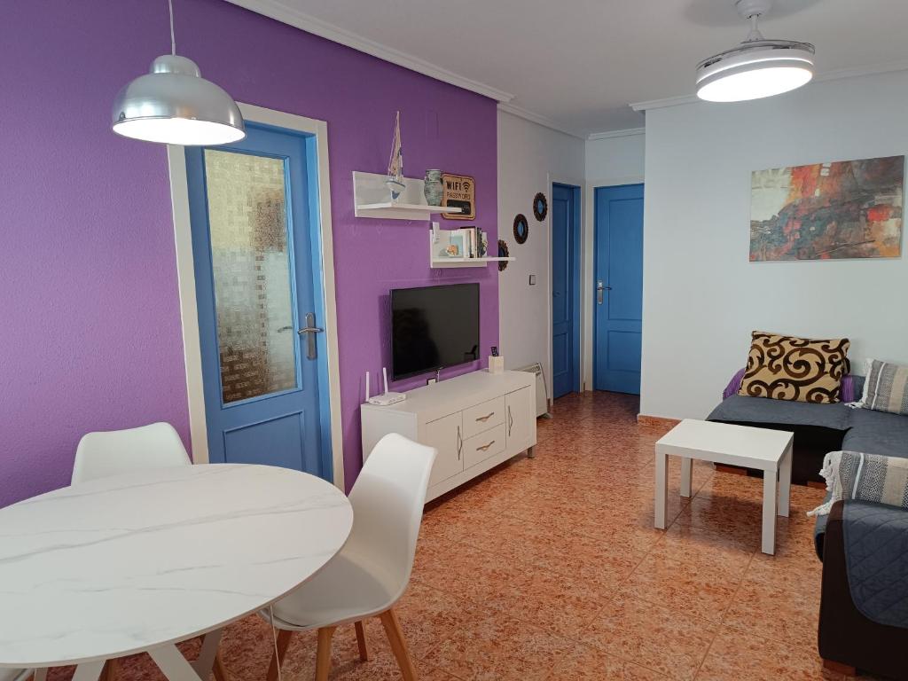 sala de estar con mesa blanca y pared morada en Alhambra Apartments, en Gran Alacant