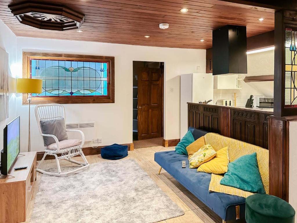 a living room with a blue couch and a kitchen at 4-bed penthouse - Old Converted Church - FREE Parking in Pontypool
