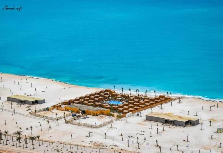 SAFY BAY RESORT & BEACH في العلمين: شاطئ رملي مع مظلات والمحيط