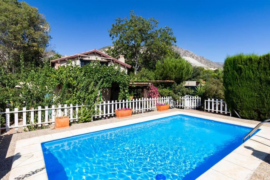 une piscine en face d'une clôture blanche dans l'établissement Casa Suryta einzigartiges Landhaus bei Granada, à Dúrcal