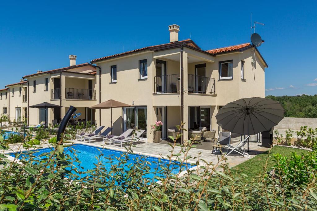 a house with a swimming pool and an umbrella at Villa Opal in Tar