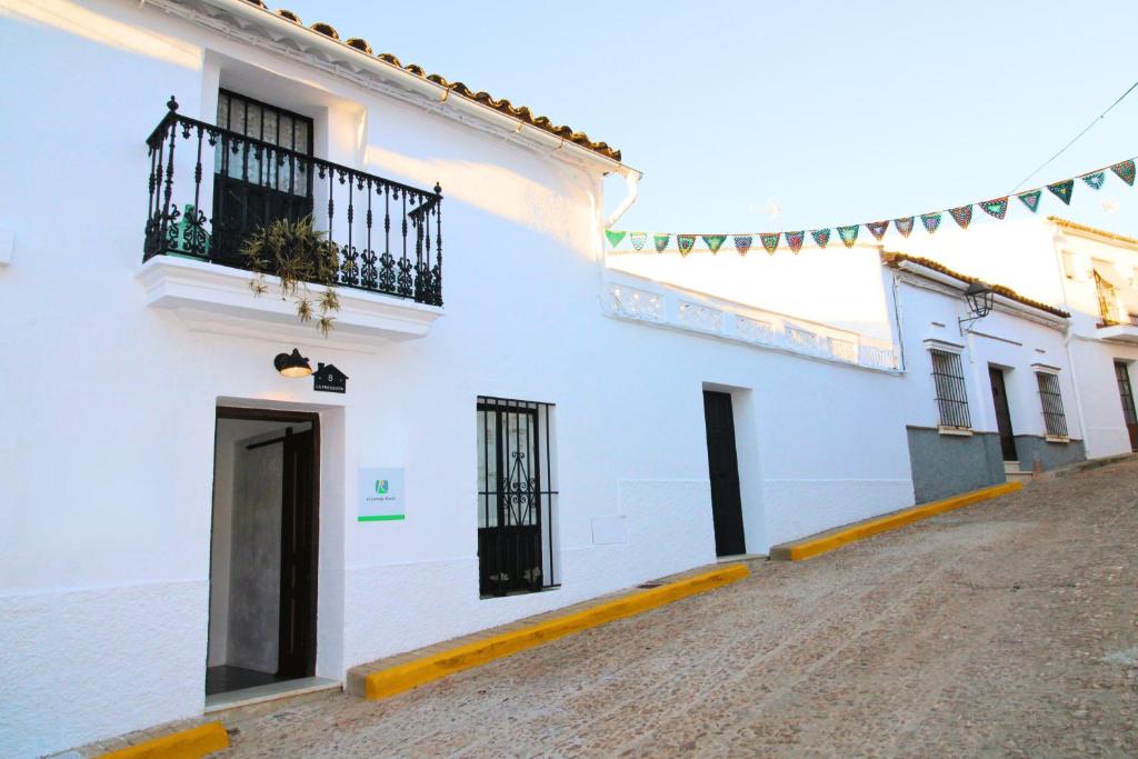 Edificio blanco con puertas negras y balcón en Casa Rural - La Fresquita, en Castaño de Robledo