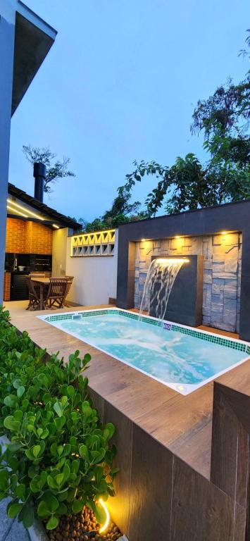 a swimming pool with a waterfall in a backyard at Casa Sunstay Garden com piscina in Bombinhas