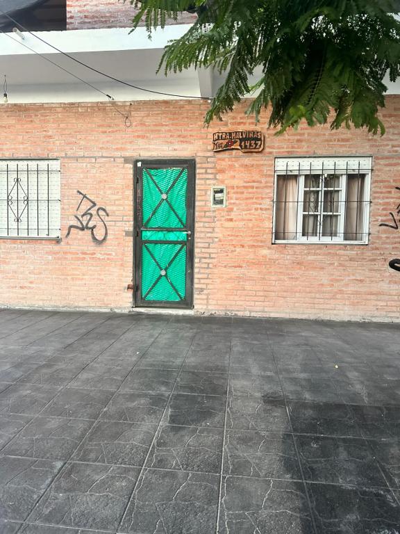 eine grüne Tür an der Seite eines Backsteingebäudes in der Unterkunft Alojamiento Mia in Monte Grande