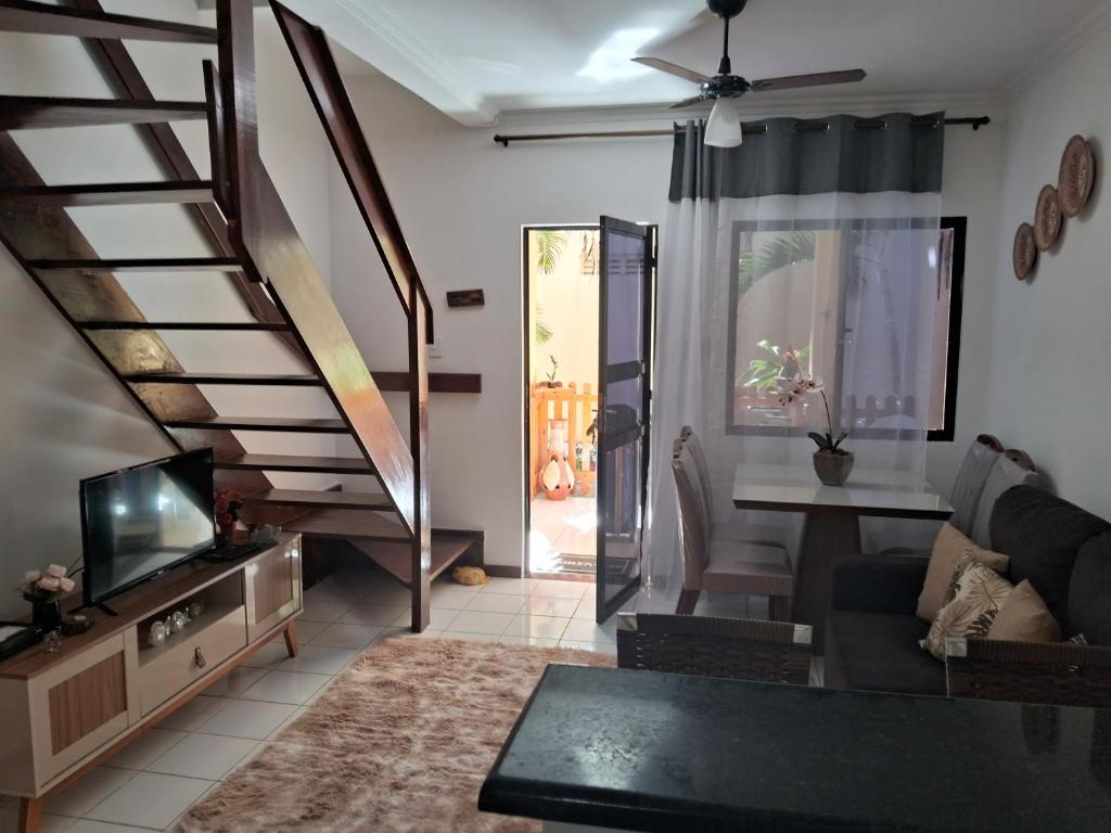 uma sala de estar com um sofá e uma televisão e escadas em VILLAGE PÉ NA AREIA em Salvador