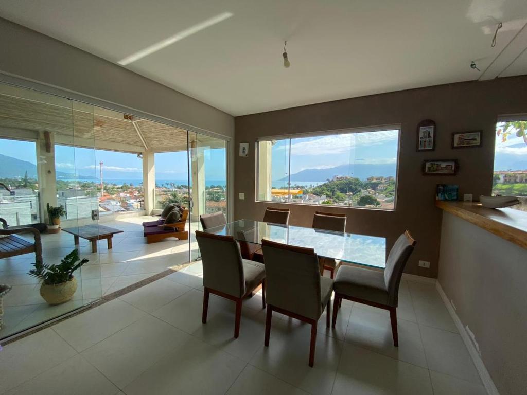 a dining room with a table and chairs and windows at Vista Maravilhosa do Mar! in São Sebastião