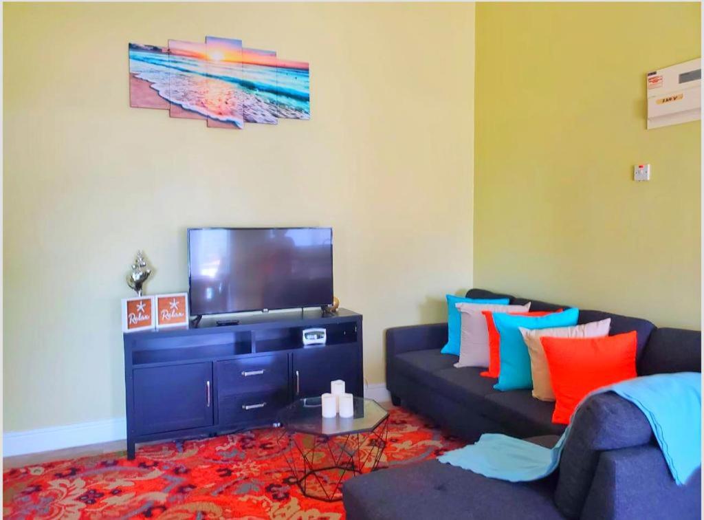 a living room with a couch and a flat screen tv at La Pelle in Soufrière